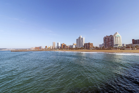 Ocean and beach against Golden Mile coastal city skyline and blue sky in Durban, South Africaの写真素材