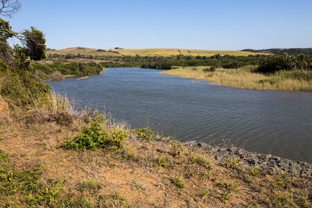 Blue meandering river with grass and vegetation on the banksの写真素材