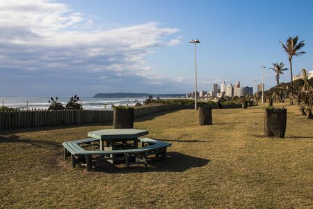 Picnic bench on grassy area overlooking sea at durban beachfrontの写真素材