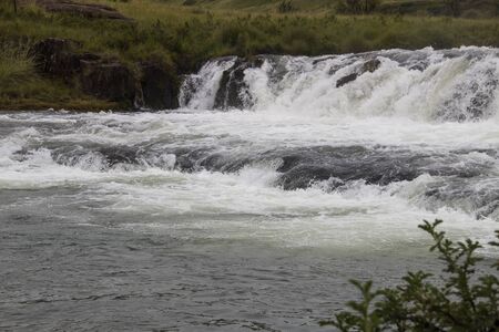 Water flowing fast over rapids of flooding riverの写真素材