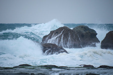 Stormy sea with big waves breaking on the rocks in the foreground