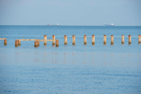 Wooden breakwaters in the sea with a blue sky background.