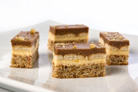 pieces of a chocolate and vanilla pudding cake with walnuts biscuit on a plate in shallow depth of fieldの写真素材