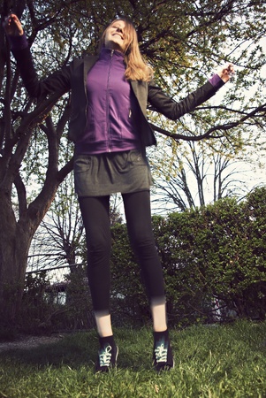 pretty young woman jumping on green grass in retro / vintage style