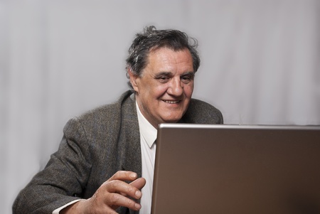 Portrait of a happy successful business man with a laptop on gray backgroundの写真素材