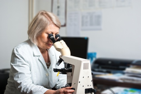 Female researcher looking through a microscopeの写真素材