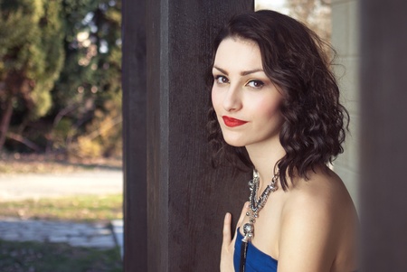 Portrait of a beautiful girl in the park leaning on a columnの写真素材