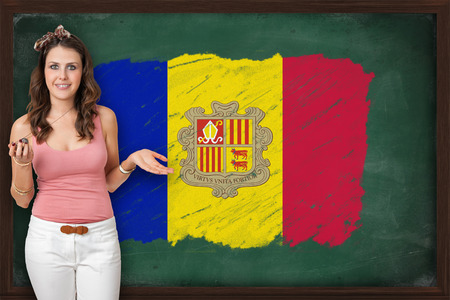 Beautiful and smiling woman showing flag of Andorra on blackboardの写真素材