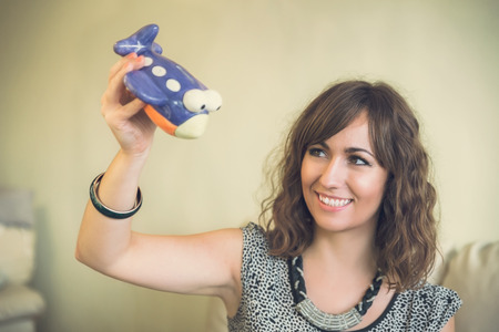 Smiling woman playing with a toy airplane as she daydreams about an upcoming summer vacation and flying to new destinationsの写真素材