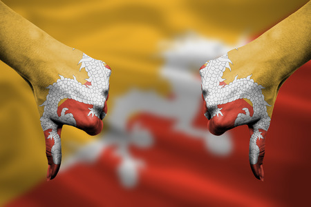 failure of Bhutan - hands gesturing thumbs down in front of flagの写真素材
