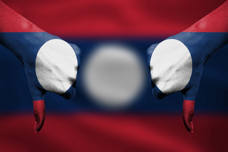 failure of Laos - hands gesturing thumbs down in front of flagの写真素材