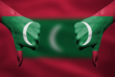 failure of Maldives - hands gesturing thumbs down in front of flagの写真素材