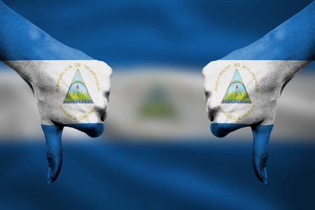 failure of Nicaragua - hands gesturing thumbs down in front of flagの写真素材