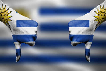 failure of Uruguay - hands gesturing thumbs down in front of flagの写真素材