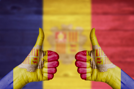 Andorra flag painted on female hands thumbs up with blurry wooden backgroundの写真素材