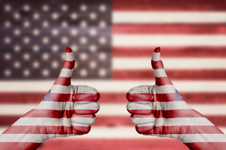 United States of America flag painted on female hands thumbs up with blurry wooden backgroundの写真素材