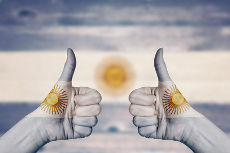 Argentina flag painted on female hands thumbs up with blurry wooden backgroundの写真素材