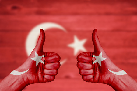 Turkey flag painted on female hands thumbs up with blurry wooden backgroundの写真素材