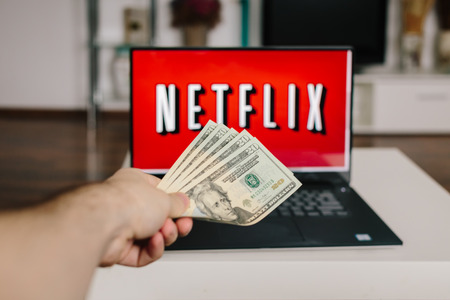 ZAGREB, CROATIA - DECEMBER 20, 2015: Netflix on laptop screen, man throwing US dollars at it. Netflix is an international provider of on-demand Internet streaming media.のeditorial素材