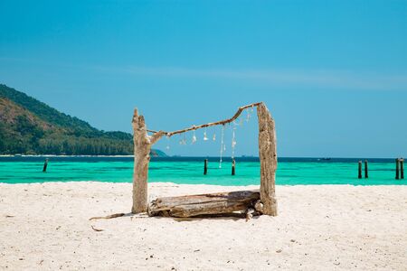 Wooden structure made with driftwood on a tropical sandy beach with turquoise blue ocean and island for an idyllic summer vacation in Koh Lipe, Thailandの写真素材