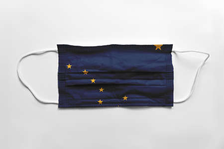 Face mask with Alaska flag printed, on white background, isolated safety conceptの写真素材