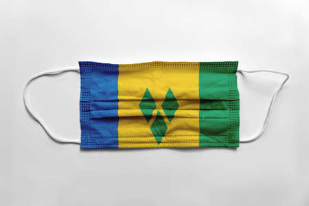 Face mask with Saint Vincent and the Grenadines flag printed, on white background, isolated. Covid-19 concept.の写真素材