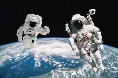 Two astronauts walking in space with earth background.の写真素材
