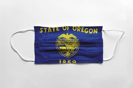 Face mask with Oregon flag printed, on white background, isolated safety conceptの写真素材