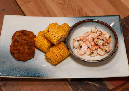 A delicious meal of prawns sweetcorn and onion bhajis on a wooden worktopの写真素材