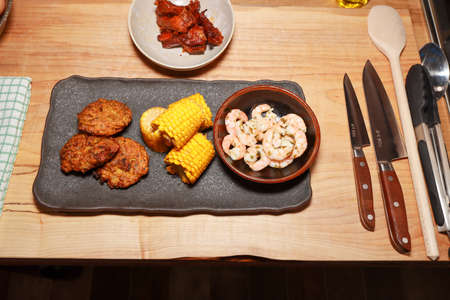 A delicious meal of prawns sweetcorn and onion bhajis on a wooden worktopの写真素材