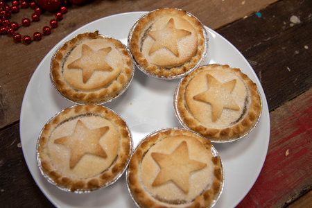 A plate of delicious Christmas mince pies on a wooden work topの写真素材