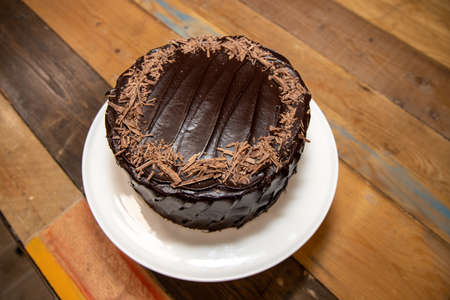 A home baked delicious chocolate cake with chocolate sprinkles on a wooden kitchen work topの写真素材