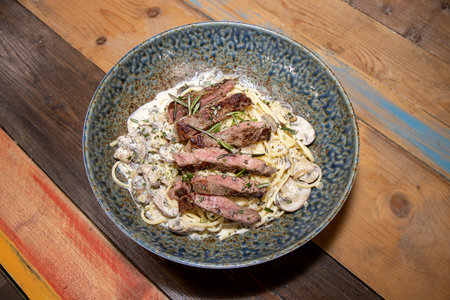 A plate of delicious steak and creamy mushroom linguineの写真素材