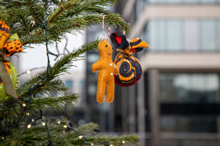 A home made Christmas decoration hanging from a Christmas tree in the shape of a a little doll