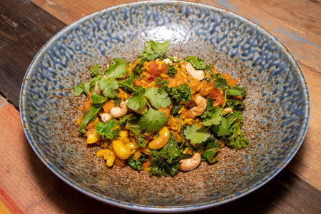 A delicious plate of Butternut Squash Biryani with cashew nuts on a wooden kitchen table or work top