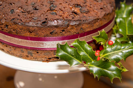 A whole delicious fruit Christmas cake surrounded by hollyの写真素材