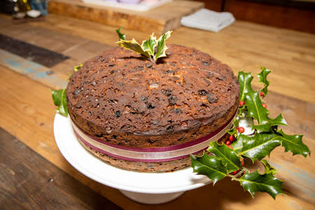 A whole delicious fruit Christmas cake surrounded by hollyの写真素材