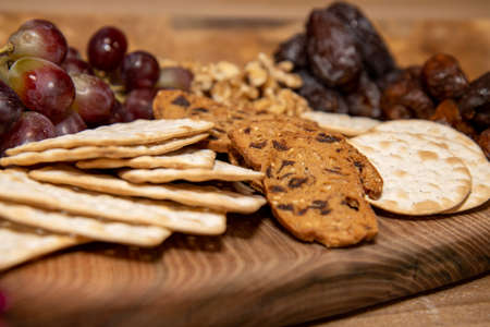 A wooden tray selection of winter cheese biscuits, nuts and grapesの写真素材
