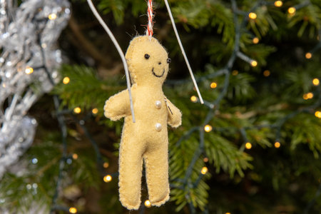 A home made Christmas decoration hanging from a Christmas tree in the shape of a a little doll
