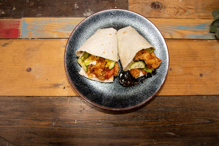 Delicious sizzling chicken fajitas with guacamole and sour cream on a wooden kitchen work topの写真素材