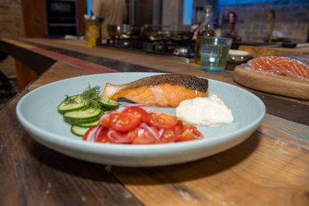 A delicious plate of Salmon and salad in a kitchen on a wooden work topの写真素材