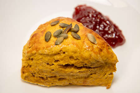 A delicious plate of a pumpkin spice scone with jam on a white background plateの写真素材