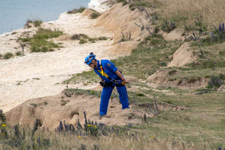 East Sussex, Beachy Head, UK 10th July 2019: Coastguard rescue men looking over the cliff at Beachy Head which is the highest chalk sea cliff in Britain and the most common suicide spots in the worldのeditorial素材