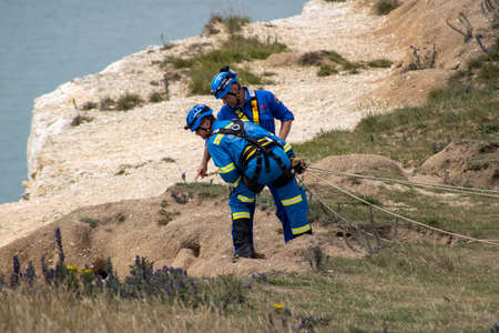 East Sussex, Beachy Head, UK 10th July 2019: Coastguard rescue men looking over the cliff at Beachy Head which is the highest chalk sea cliff in Britain and the most common suicide spots in the worldのeditorial素材