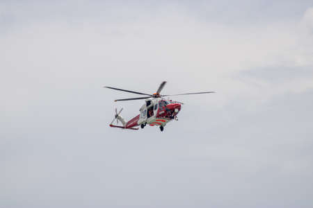 East Sussex, Beachy Head, UK 10th July 2019: The HM Coastguard Rescue Helicopter attending an incident on the Beachy Head cliffs flying in the sky on a bright cloudy day over the ocean.のeditorial素材
