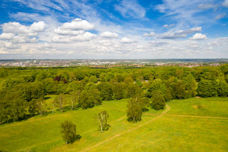Aerial photo of the city of Leeds viewed from the village of Middleton and Middleton Park on a sunny day with white clouds in the sky and a lot of green trees in the summer timeの写真素材
