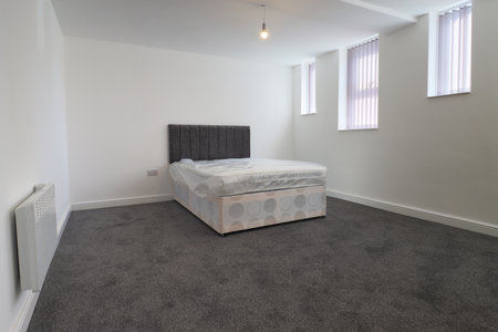 A newly decorated typical British UK bedroom with a large bed, with white walls, grey carpet with blinds at the window.の写真素材