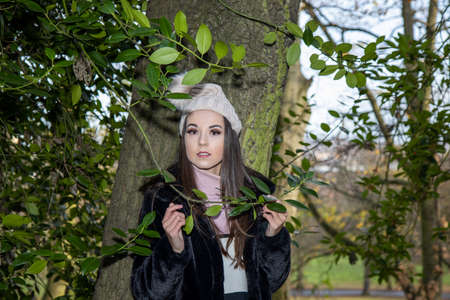 A young attractive woman with long brown hair in the winter time in a woodland park wearing a black coatの写真素材