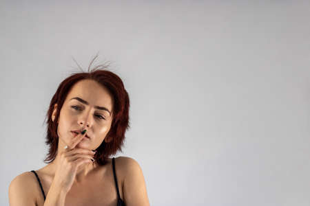 A young female attractive caucasian model with album red hair in a studio with a white background wearing a black dress.の写真素材