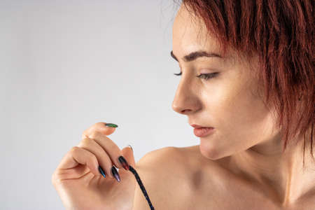 Studio photo of an attractive woman in a studio with a white background wearing red lingerie pulling her bra strap down from her shoulder seductively.の写真素材